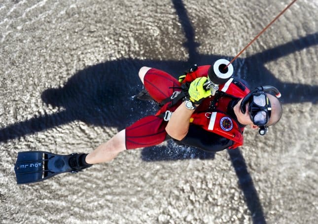 rescue swimmer brett fogle hangs from a helicopter hoist cable over the river in Elizabeth City North Carolina