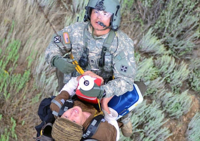 rescuer riding up to a helicopter on a lifesaving systems rescue seat