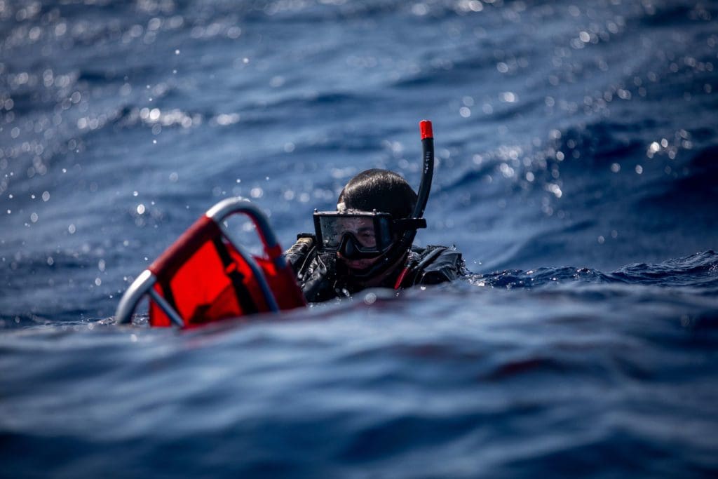 220717-N-XH769-1198 ATLANTIC OCEAN (July 17, 2022) Aviation Boatswain's Mate (Handling) 3rd Class Andrew Gabris swims with a stretcher during a search and rescue training exercise near the Wasp-class amphibious assault ship USS Kearsarge (LHD 3) July 17, 2022. The Kearsarge Amphibious Ready Group and embarked 22nd Marine Expeditionary Unit, under the command and control of Task Force 61/2, is on a scheduled deployment in the U.S. Naval Forces Europe area of operations, employed by U.S. Sixth Fleet to defend U.S., allied and partner interests. (U.S. Navy photo by Mass Communication Specialist 3rd Class Ryan Clark)